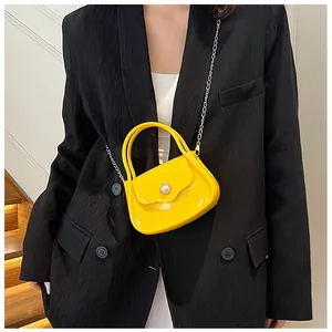 Detail of yellow jelly bag with pearl buckle and gold chain strap worn by a model