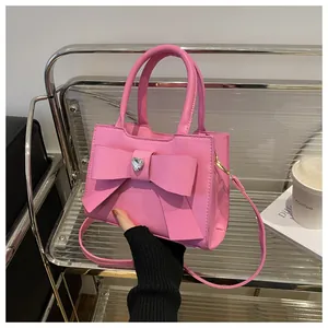 Detailansicht der rosa Schleifen-Handtasche mit Herz-Strassstein und Leder-Handgriffen