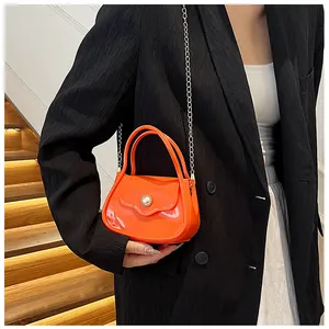 Close-up of vibrant orange jelly handbag with pearl buckle and silver chain strap