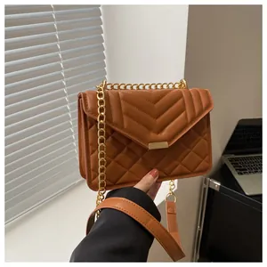 Close-up of brown quilted crossbody bag with golden chain strap and metallic lock