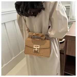 Detail of light brown crocodile pattern leather handbag with golden square lock and pleated handle