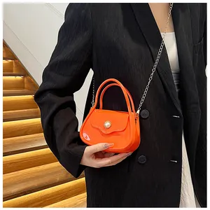 Detail of orange jelly crossbody bag with pearl embellishment and silver metal chain strap