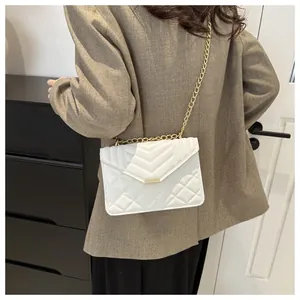 Close-up of white quilted crossbody bag with gold chain strap on model shoulder