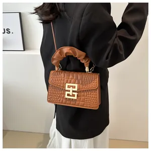 Detail of brown crocodile pattern handbag with pleated handle and golden square buckle