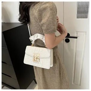 Detail of white crocodile pattern PU handbag with golden clasp and ruched handle design