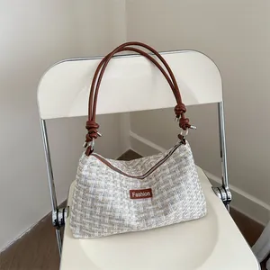 Borsa a tracolla in tweed alla moda con tracolla a nodo su sfondo sedia color crema