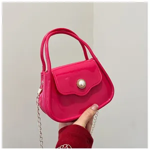 Detail view of mini rose red jelly bag with elegant pearl clasp and gold chain strap