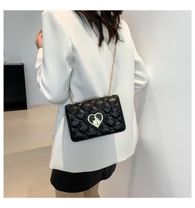 Détail d'un sac à bandoulière matelassé noir avec serrure cœur dorée et chaîne élégante