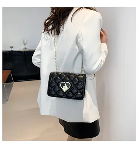 Détail du sac bandoulière en cuir noir matelassé avec fermoir cœur doré et chaîne