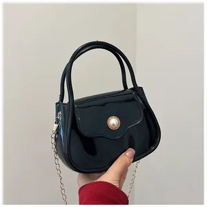 Close-up of black jelly bag featuring gold chain strap and pearl buckle detail