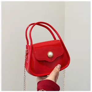 Detail of red jelly bag featuring mirror-like finish, pearl clasp, and metal chain strap