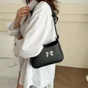 Elegant black PU shoulder bag with silver bow accent and knotted strap on model