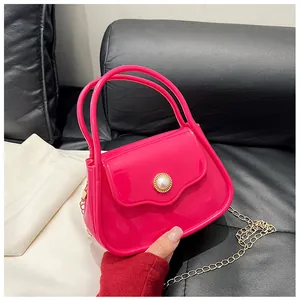 Detail of a bright pink jelly handbag with pearl button and gold chain strap