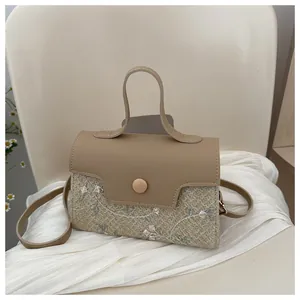 Detail of woven fabric handbag with floral embroidery and khaki leather top handle