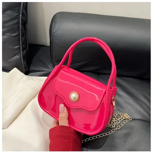 Detail of rose red jelly bag featuring a large pearl embellishment and gold chain strap