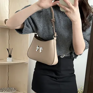 Beige leather underarm bag with silver bow accent and knotted shoulder strap