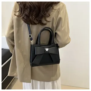 Detail der schwarzen Schleifenhandtasche mit Herz-Strass und verstellbarem Gurt am Model