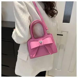 Detail der rosa Schleifen-Handtasche mit Herz-Kristall und PU-Lederstruktur an einem Modell