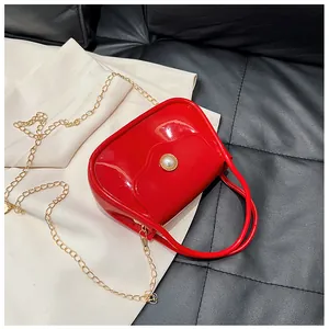 Close-up of red glossy jelly bag featuring pearl buckle and gold metal chain