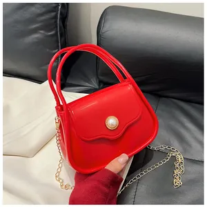 Close-up of mini red jelly bag featuring a large pearl clasp and golden chain strap