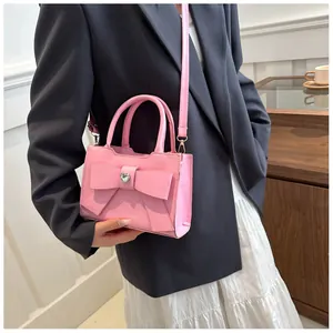 Rosa Handtasche mit Schleife und Herzschnalle, kombiniert mit einem schicken Blazer