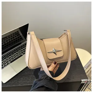 Détail du fermoir en étoile argenté sur un sac baguette chic de couleur beige nude