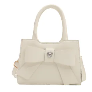 Modische cremeweiße Handtasche mit Schleife und Kristallherz für elegante Damen