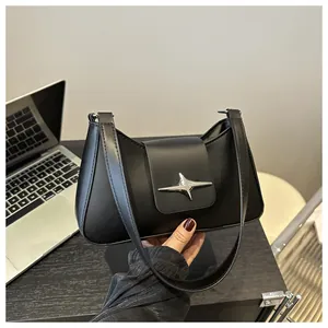 Détail d'un sac baguette noir mat avec boucle étoile argentée et bandoulière en cuir