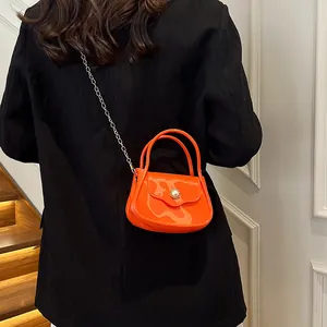 Mini orange jelly handbag with pearl buckle and metal chain strap on black blazer
