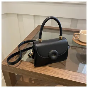 Detail of black leather small square bag with elegant gold ring clasp and handle