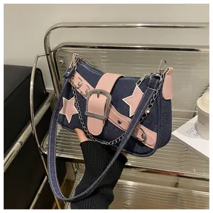 Detail of Y2K denim shoulder bag featuring pink star patches and metallic buckle strap