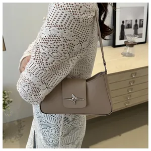 Détail du sac baguette beige montrant la boucle étoile argentée et le cuir lisse fini