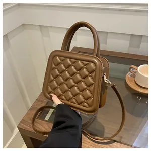 Close-up of dark brown quilted crossbody bag with adjustable strap and top handle