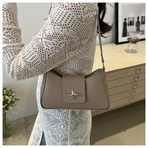 Détail du sac baguette en cuir minimaliste avec fermoir étoile argenté et fine bandoulière