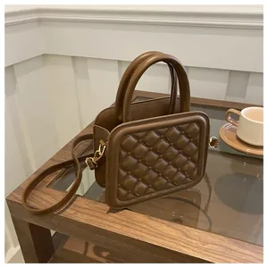 Detailed close-up of brown quilted faux leather handbag on a wooden coffee table