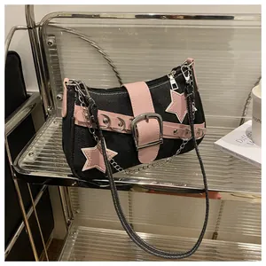 Detail of denim shoulder bag with pink leather stars, metal rivets and chain strap