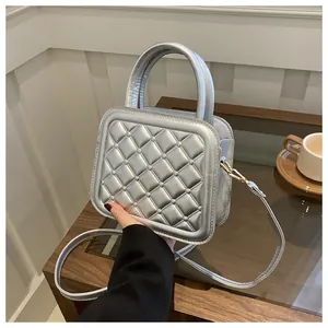 Detail of silver quilted crossbody bag with metallic texture on a wooden surface