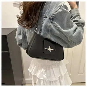 Détail du sac baguette noir en similicuir avec boucle étoile argentée et bandoulière chic