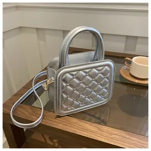 Detail of silver quilted crossbody bag featuring metal rivets and textured metallic finish