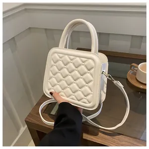 Detailed view of quilted white crossbody bag with pearl accents on a wooden table