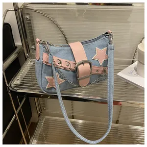 Detail of denim shoulder bag with pink star patches and metallic chain buckle