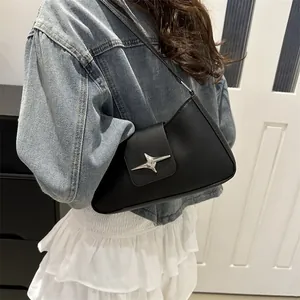 Sac baguette chic en cuir noir mat avec boucle en étoile porté avec une veste en jean