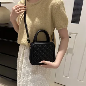 Classic black quilted square handbag with top handle and adjustable shoulder strap