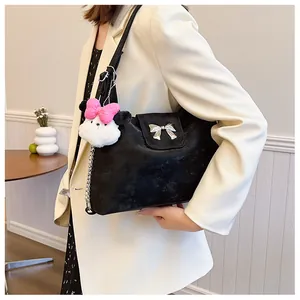 Detail of black crossbody bag with silver bow accent and plush charm hanging on side