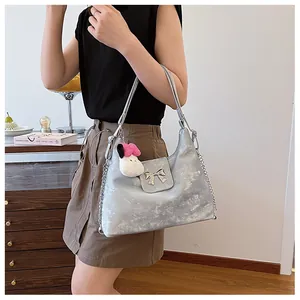 Detail of silver metallic hobo bag featuring a metal bow and pink plush rabbit charm