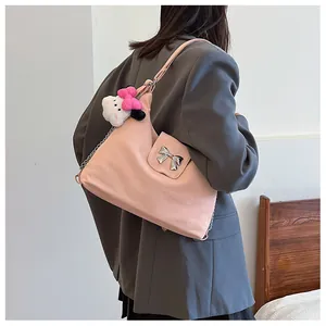 Detailed back view of pink faux suede tote bag with metallic bow and plush cat charm