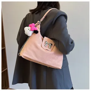 Detail of pink tote bag with silver bow accent and metallic chain strap on model