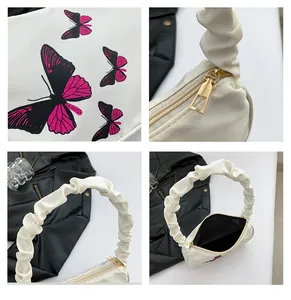 Detailed view of butterfly print, gold zipper, and ruched handle on a white shoulder bag