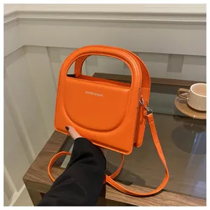 Detail view of the orange PU leather handbag featuring structure handles and silver hardware