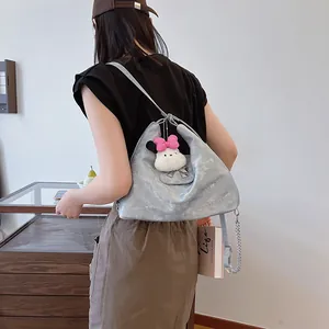 Silver metallic hobo bag with chain strap and plush bunny charm on a model